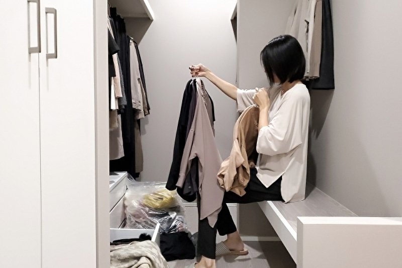 クローゼットで洋服を収納している女性