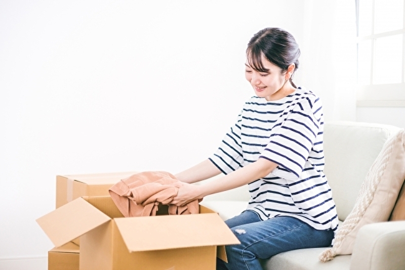 しまむらの古着回収 ダンボールに洋服を入れる女性