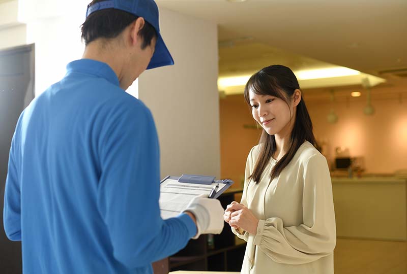 蕨市で粗大ゴミを回収業者に依頼するメリットを知って、業者に相談している女性